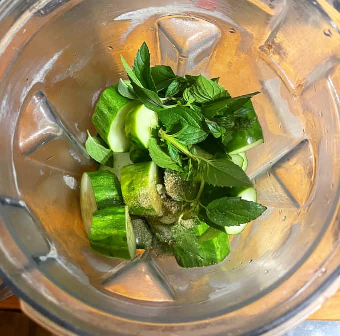 Cucumbers, mint and other ingredients in blender jar.