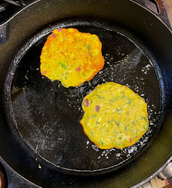 Cucumber pancakes cooking in cast iron griddle.