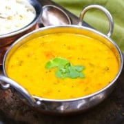 Authentic Indian toor dal served in a traditional karahi bowl, garnished with cilantro, with rice on the side.