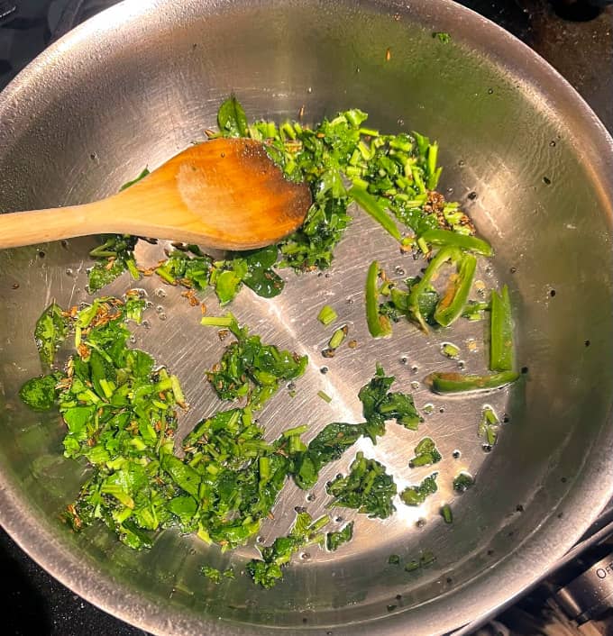 Cilantro with mustard seeds and cumin seeds in pan.