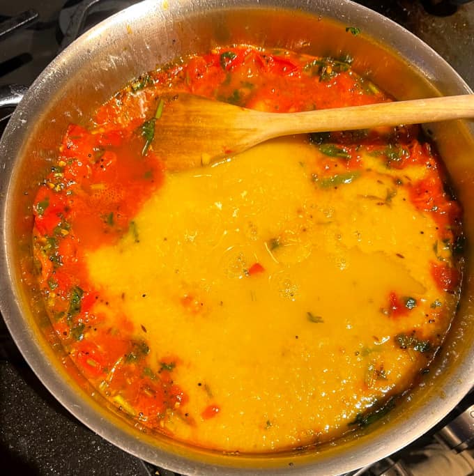 Cooked lentils or dal added to tomatoes and other spices in pan.