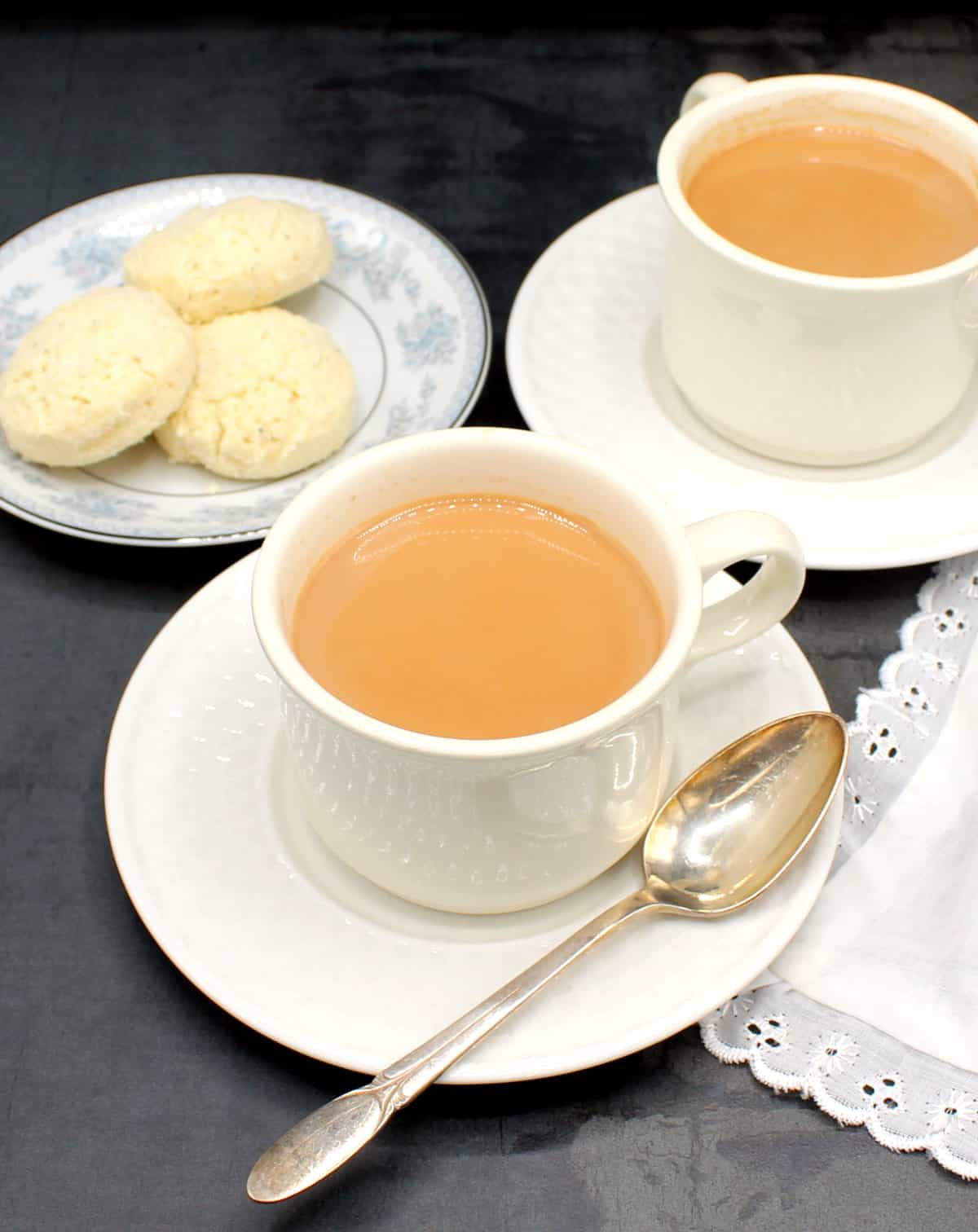 Masala chai tea in cups with a plate of cookies.