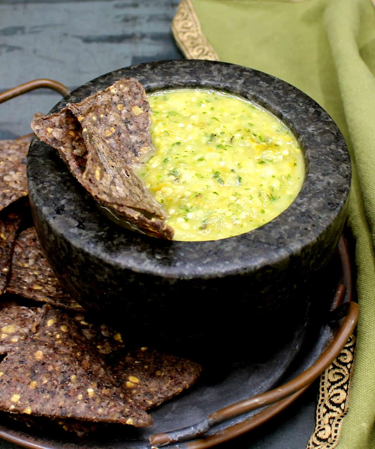 Salsa verde in stone molcajete bowl with tortilla chips.
