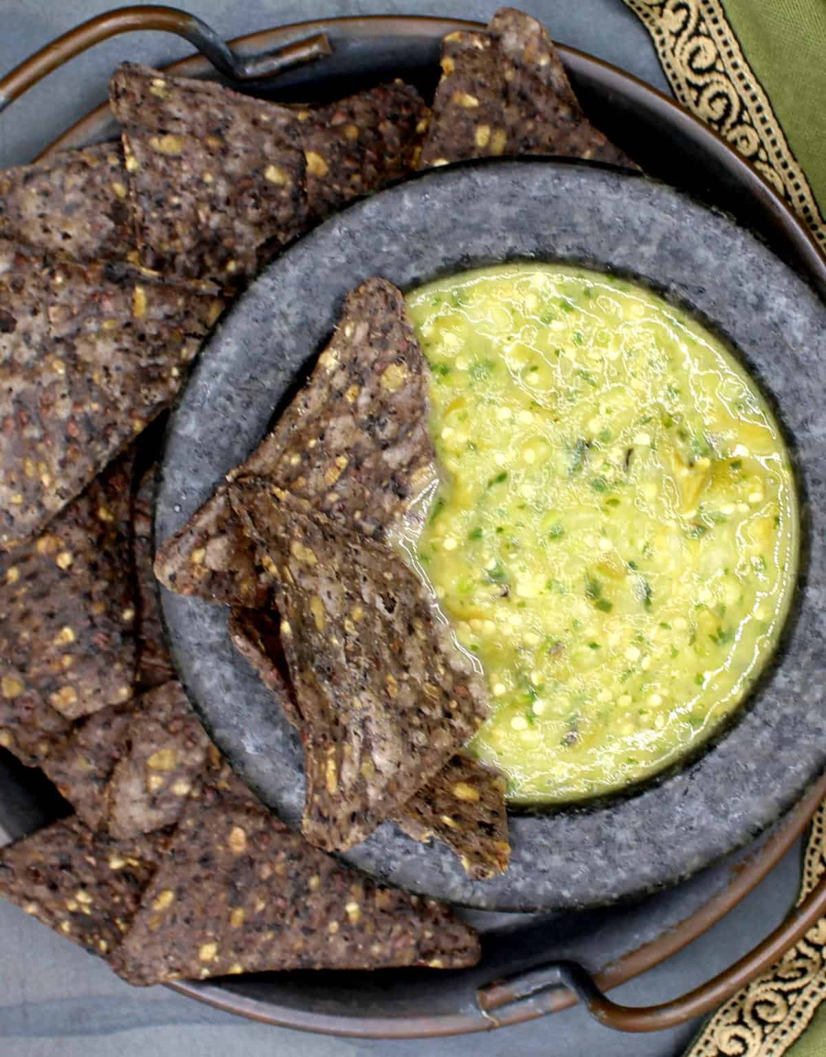 Salsa verde in molcajete bowl with black bean tortilla chips.