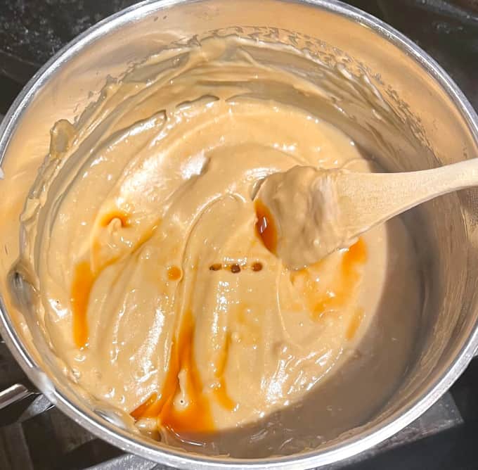 Vanilla extract added to condensed milk in saucepan.