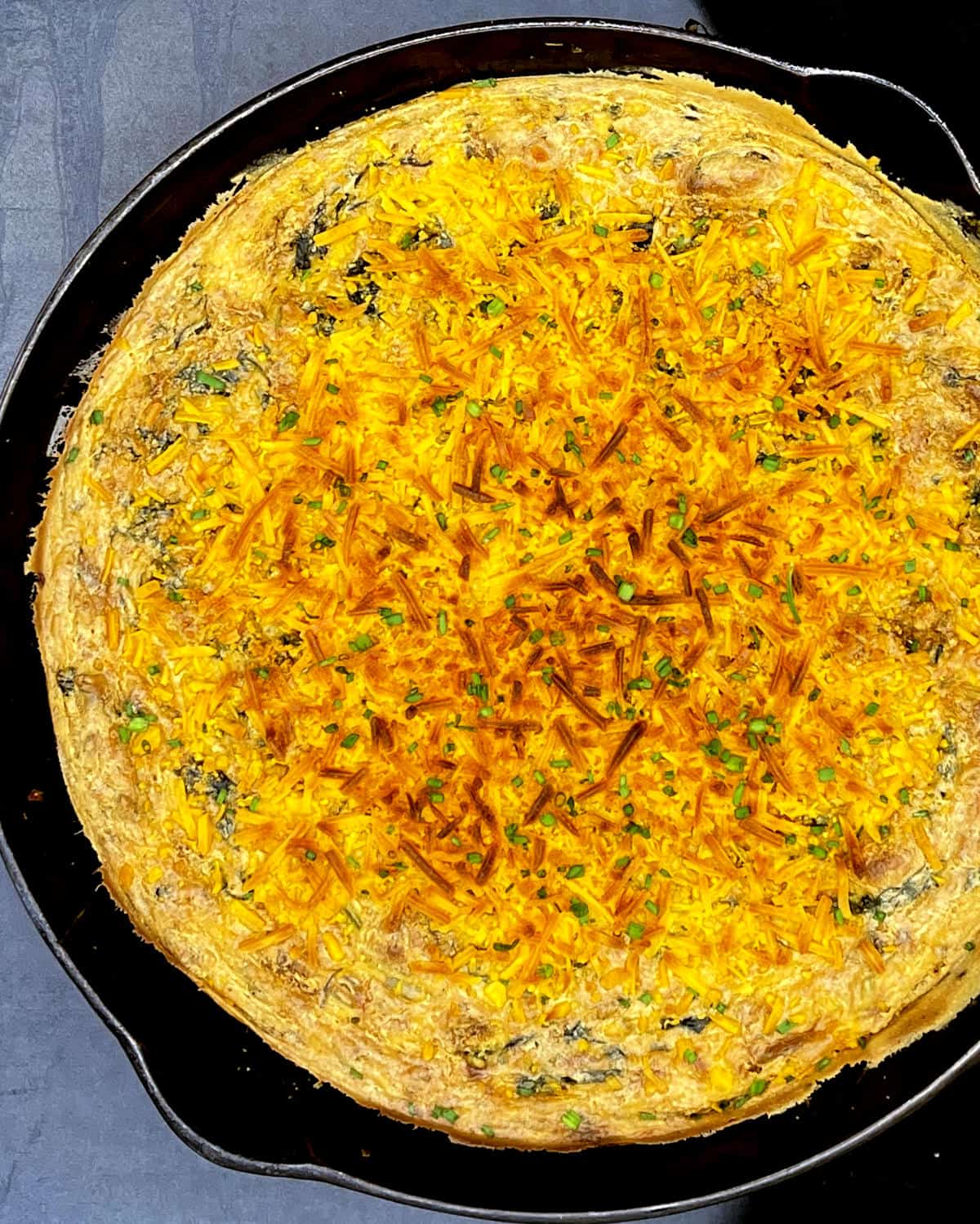Vegan low carb breakfast casserole with crackly cheese topping in black cast iron skillet.