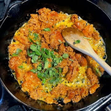 Herbs added to sausage in skillet.