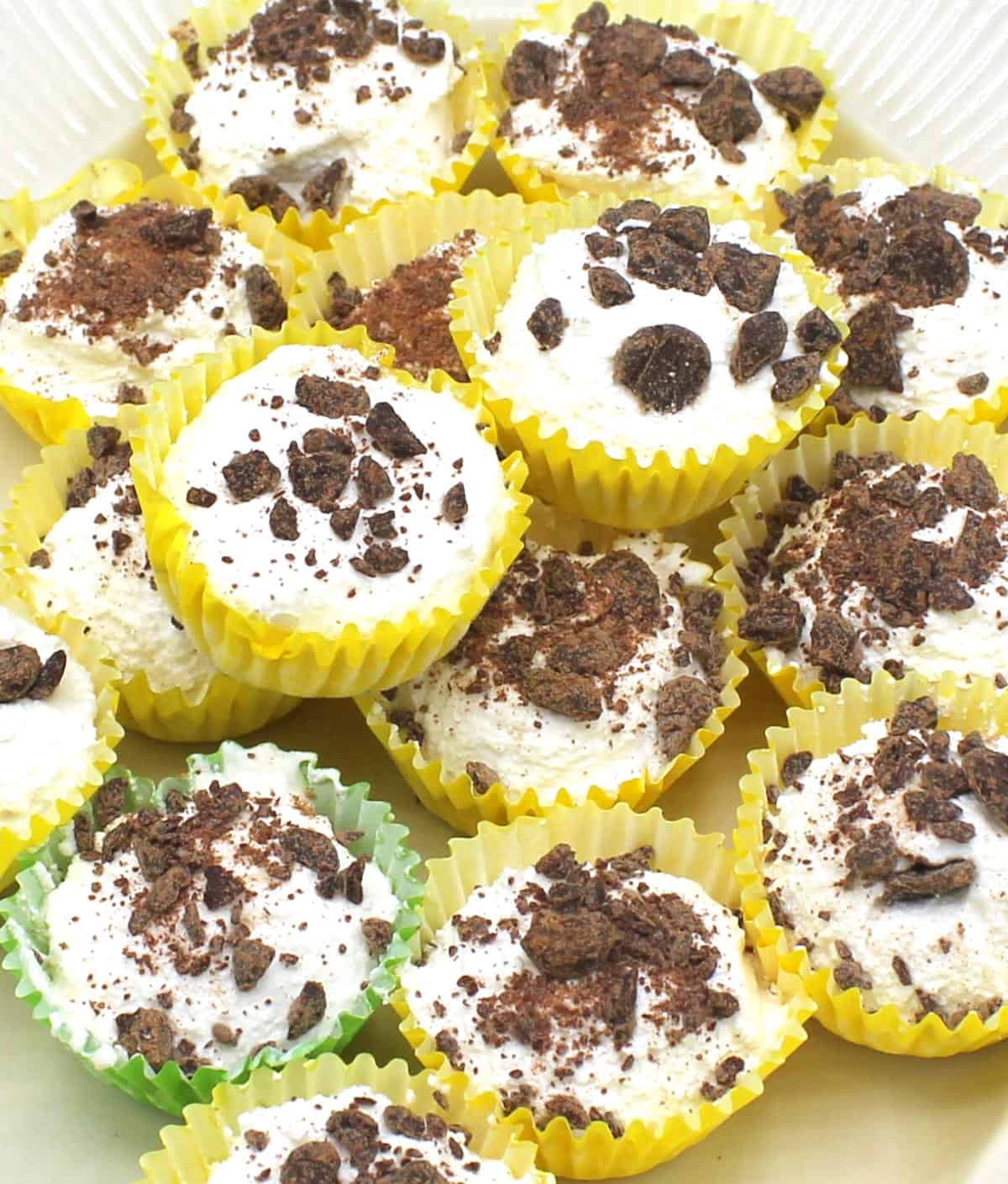 Vegan mini cheesecake bites with chocolate pieces in yellow cupcake liners.