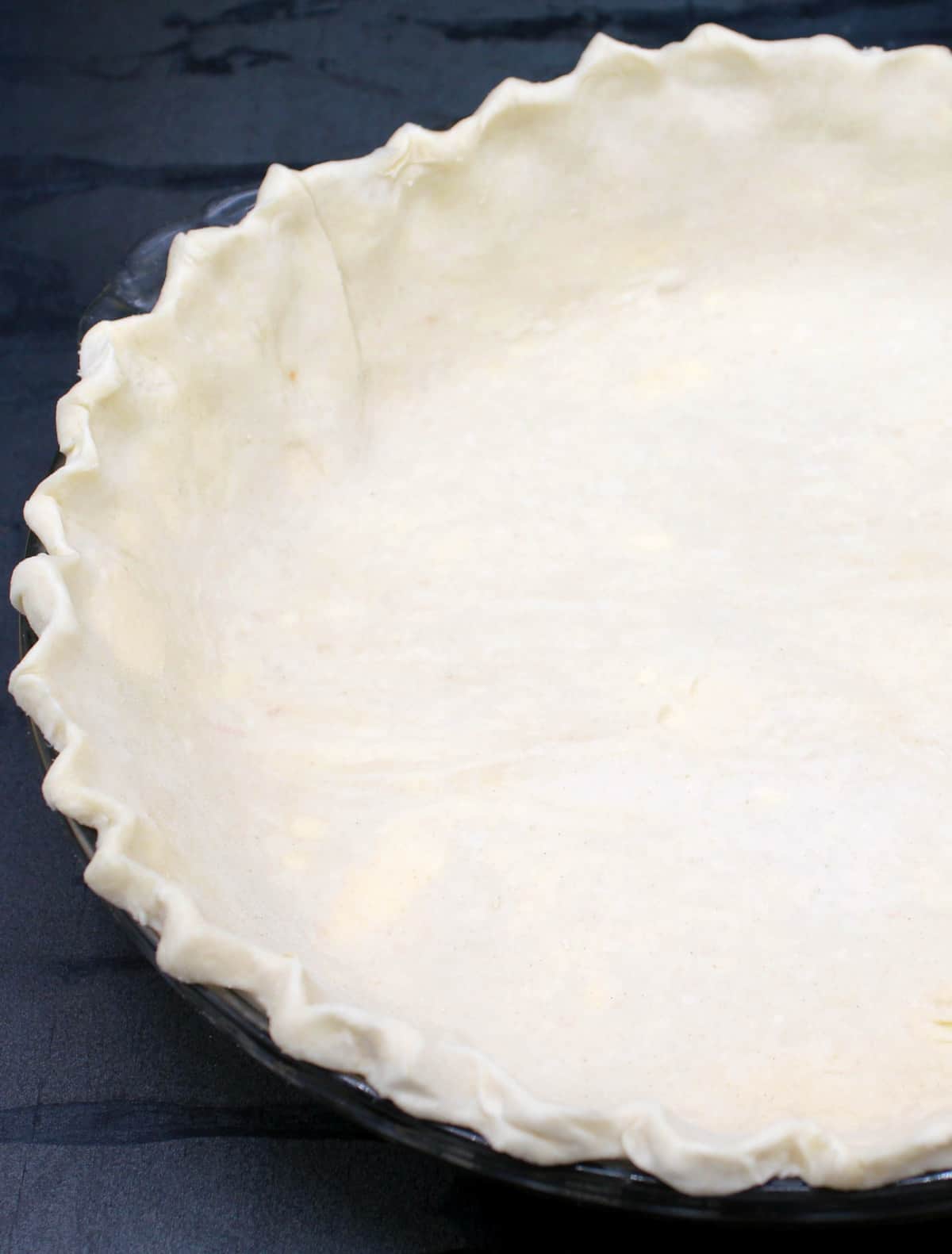 Vegan pie crust with fluted edge in glass deep dish pie plate.