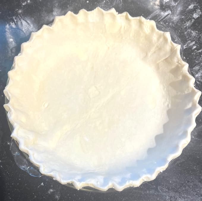 Pie dough fluted in pie plate.