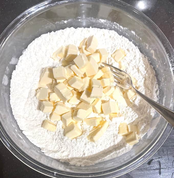 Cubed butter added to flour in glass bowl.