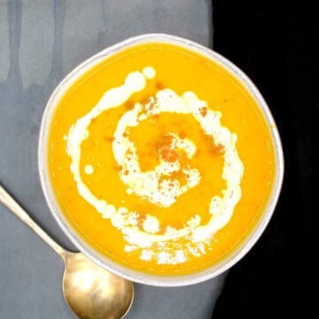 Butternut squash soup in bowl with a swirl of pumpkin cream and cinnamon.