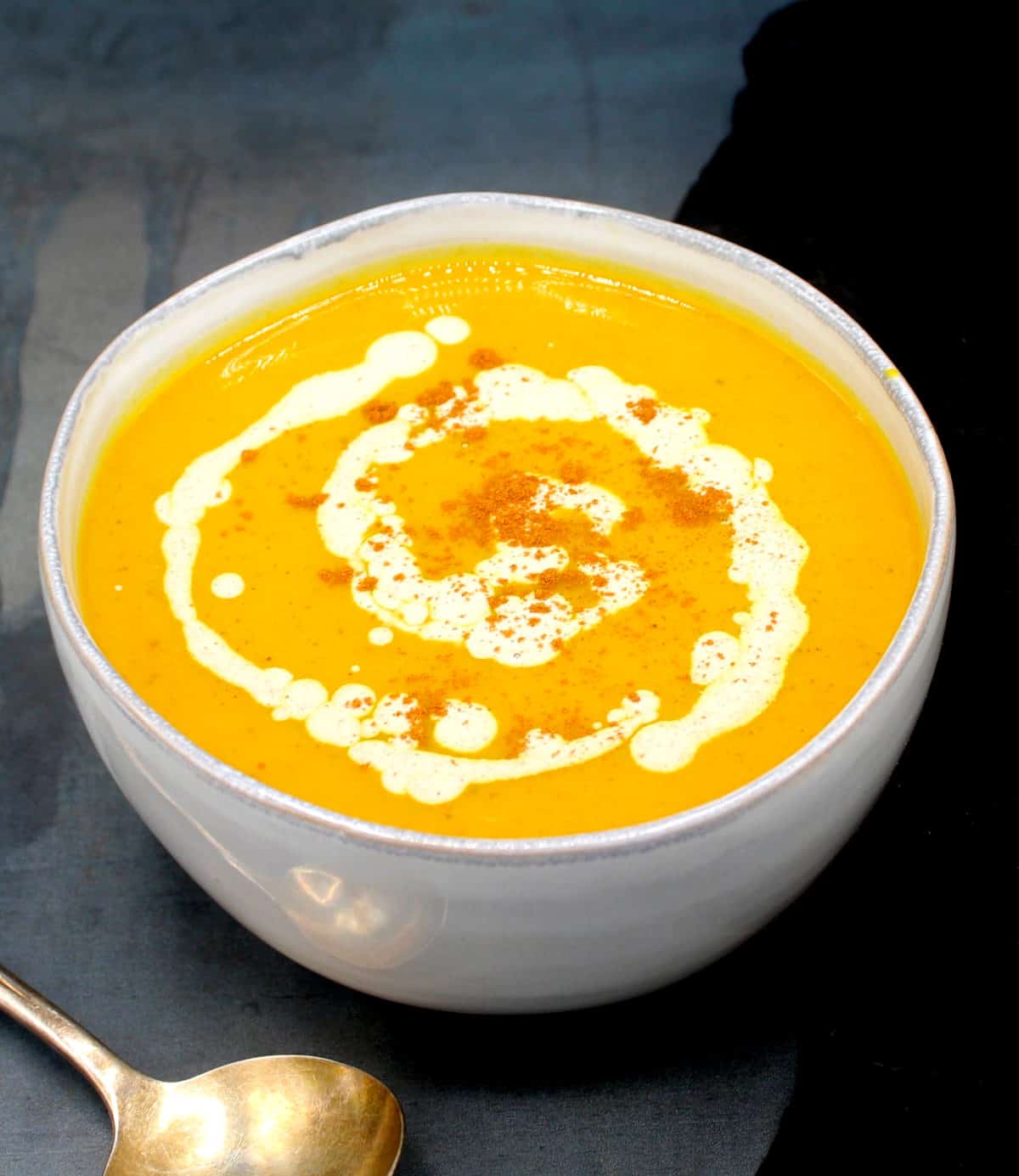 A delicious curried butternut squash soup in bowl with cinnamon cream. 