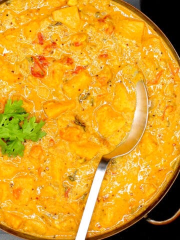 Creamy butternut squash curry in copper serving pan with spoon.