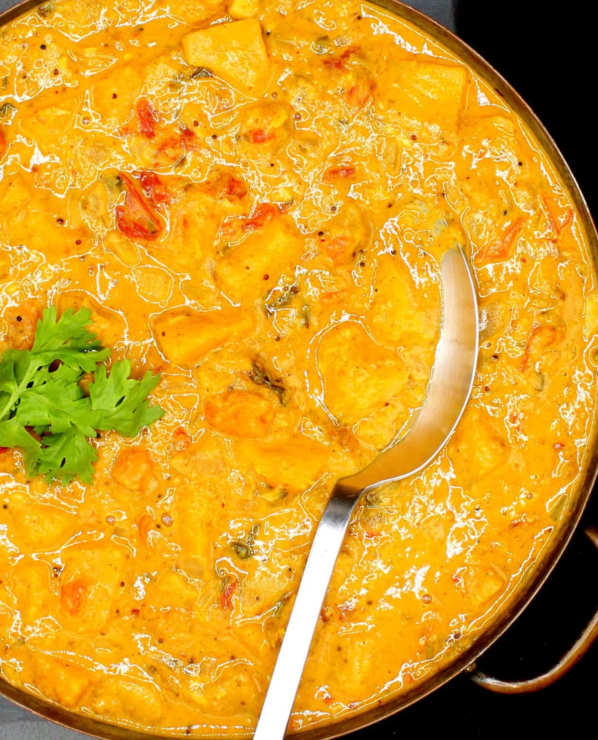 Creamy butternut squash curry in copper serving pan with spoon.