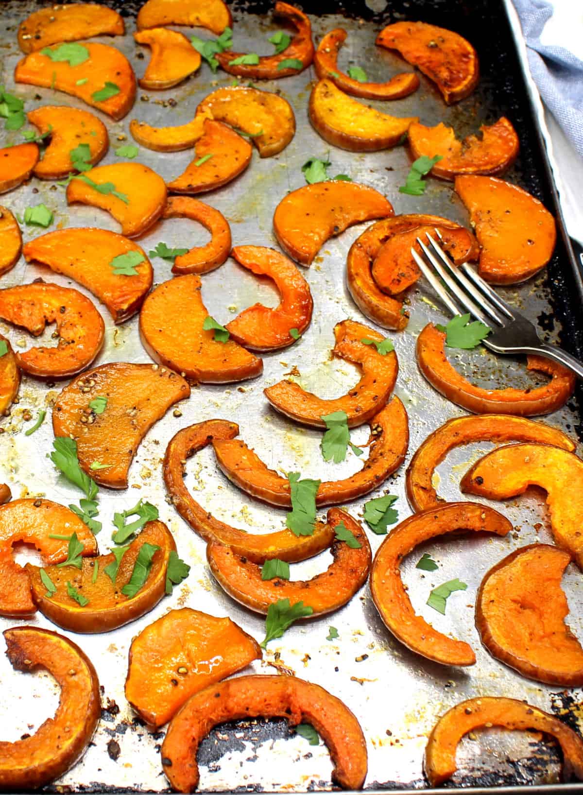 Slices of roasted butternut squash on baking sheet with fork.