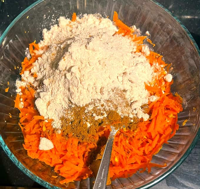 Salt and pickling spices added to carrots and ginger in bowl.