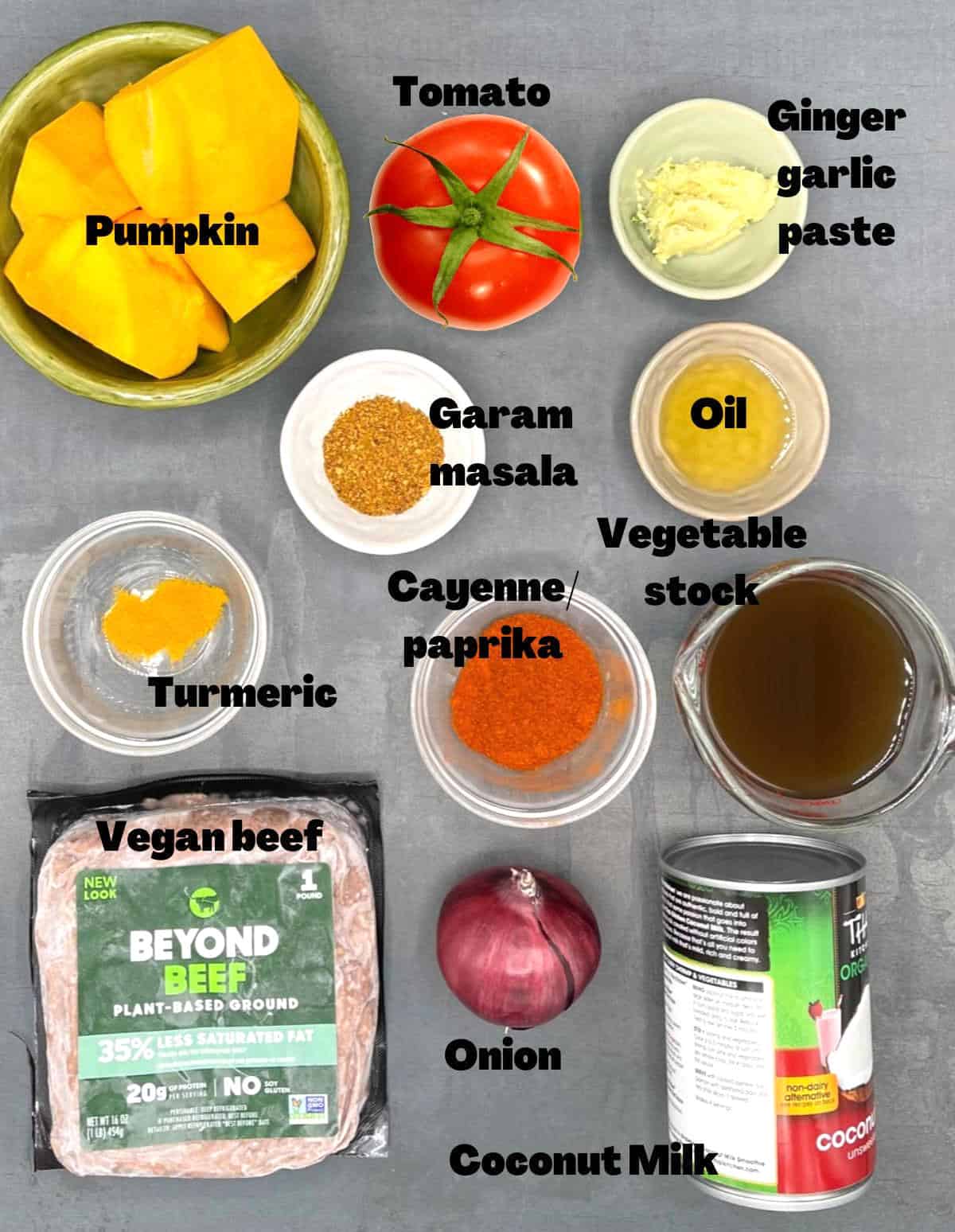 Ingredients for pumpkin curry in bowls on gray background