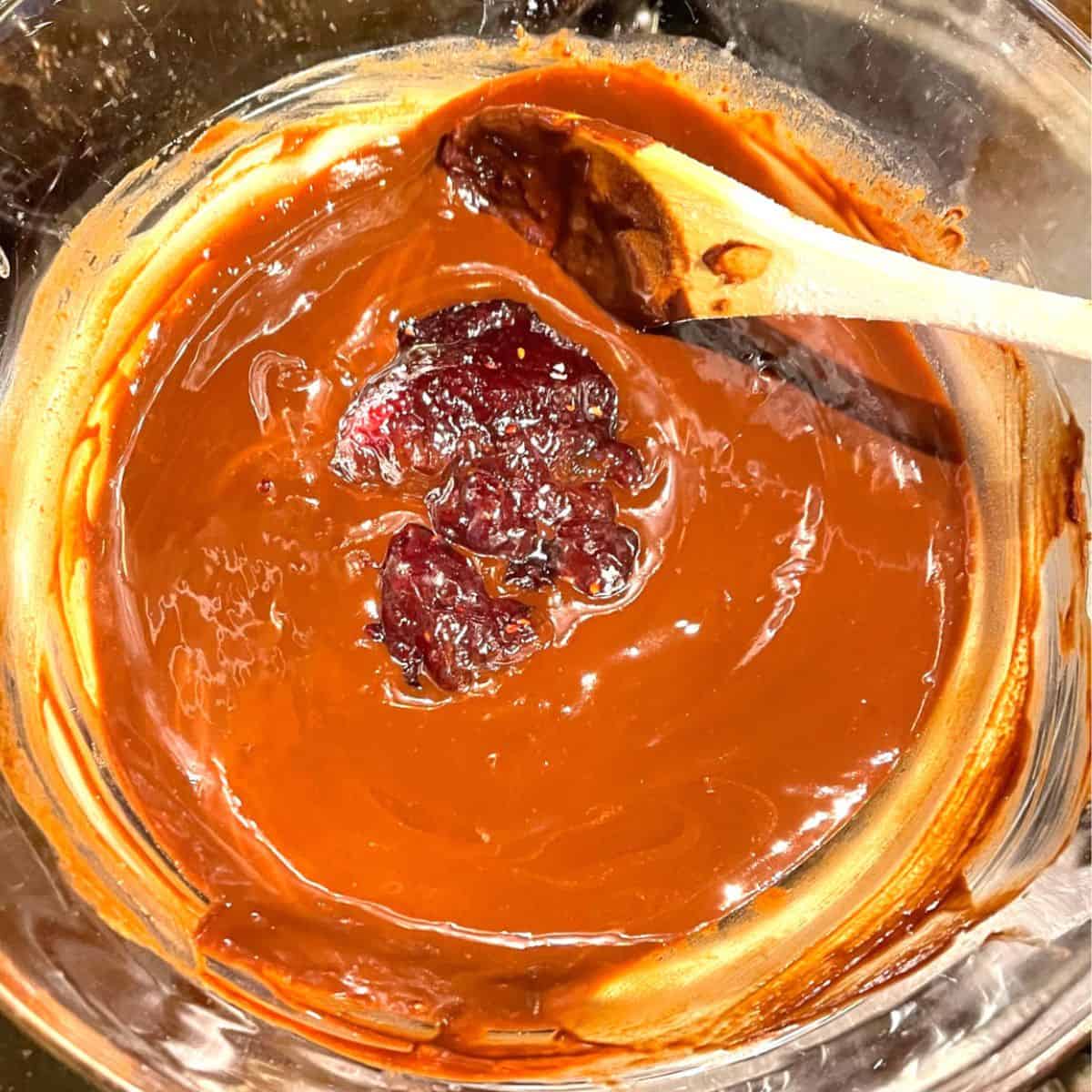 Raspberry jam added to melted chocolate in double boiler.