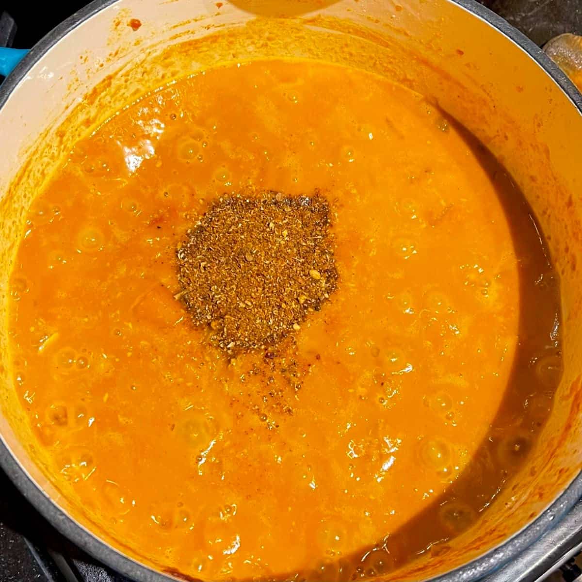 Garam masala added to pumpkin curry in Dutch oven.