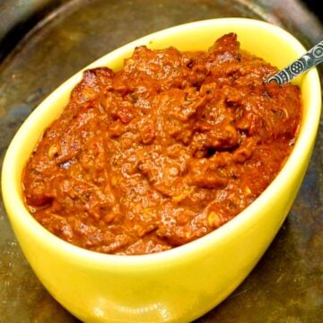 Harissa paste in yellow bowl with spoon.