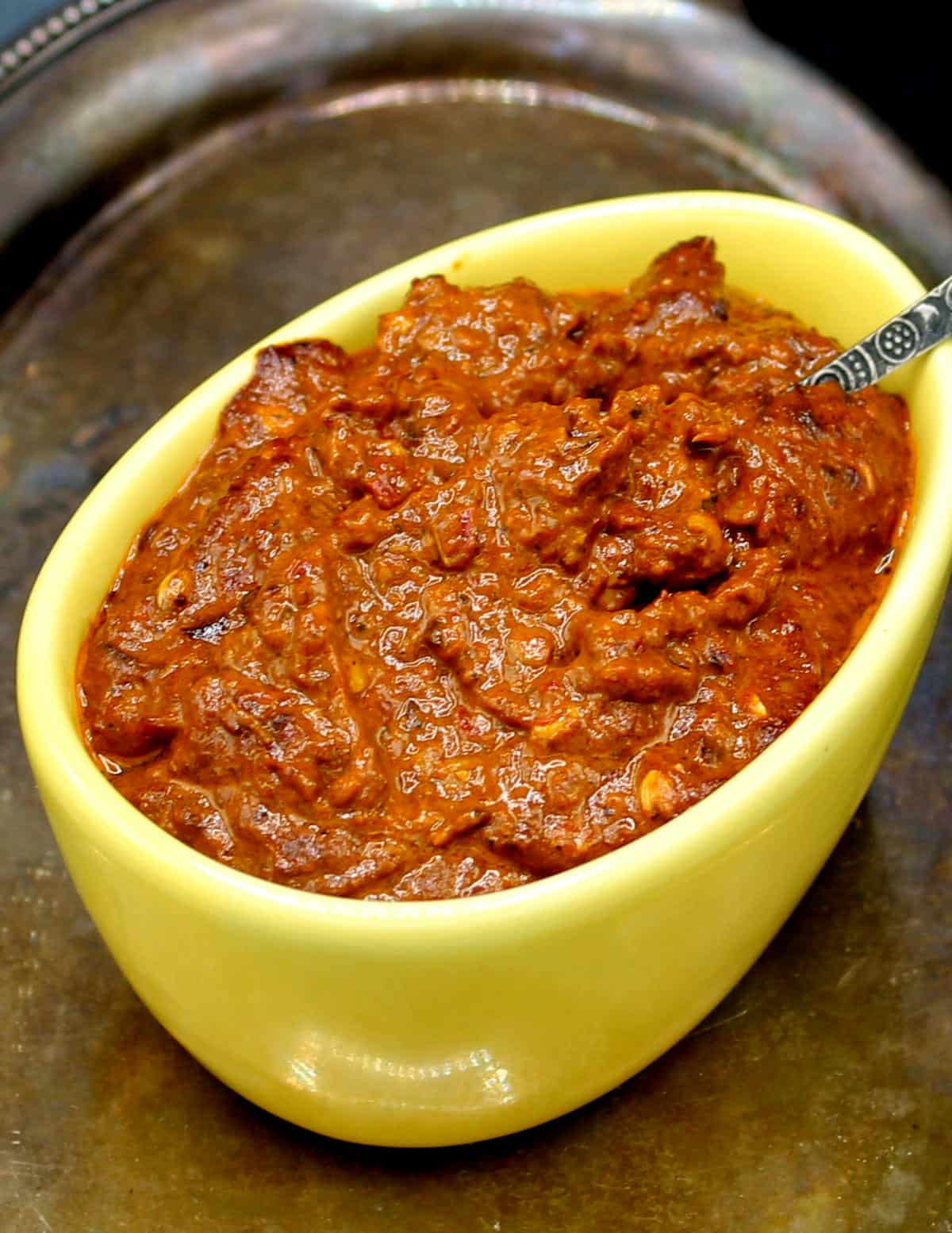Harissa paste in a yellow bowl with spoon.