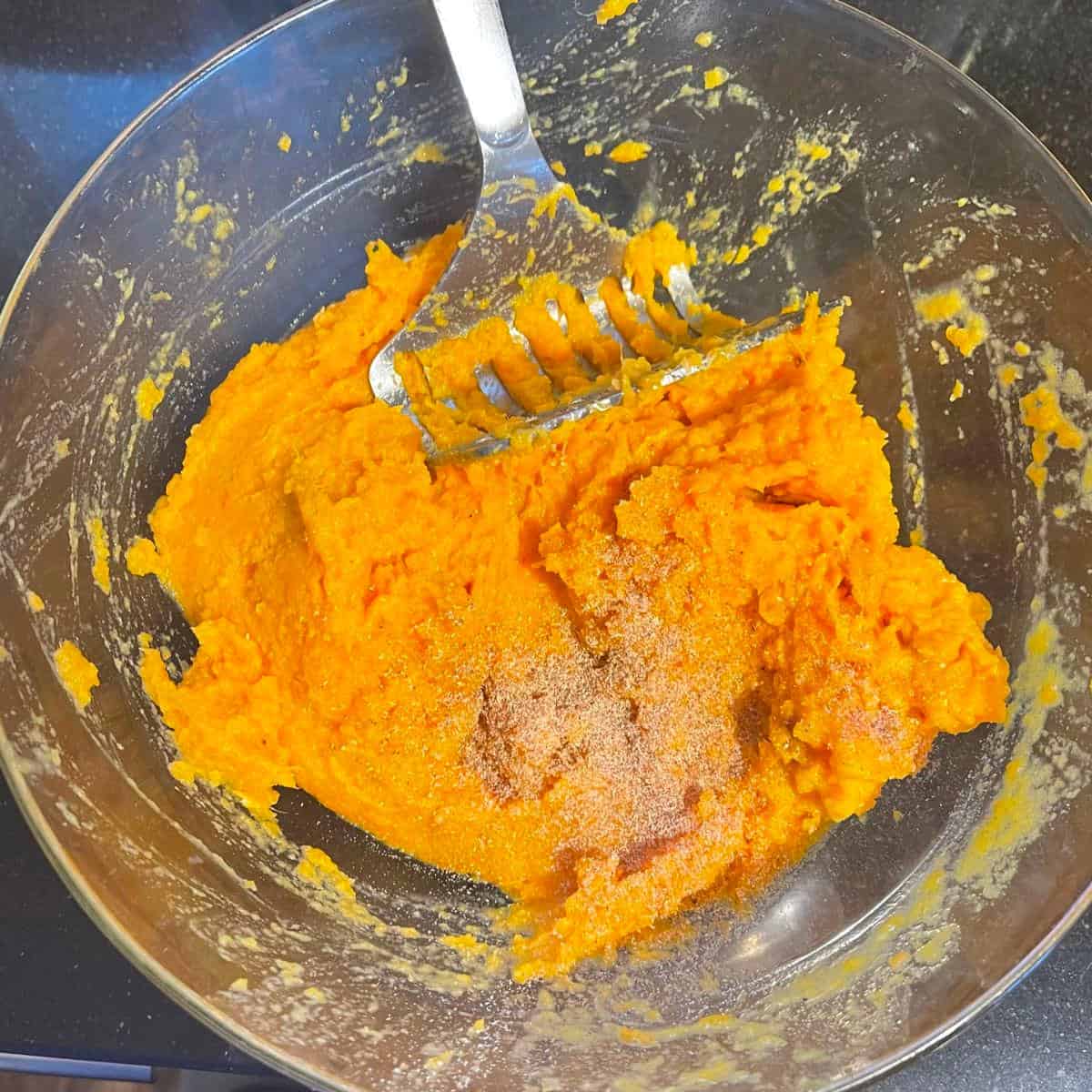 Nutmeg added to mashed sweet potatoes in bowl.