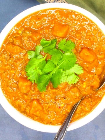 Pumpkin curry with cilantro garnish in bowl with spoon.