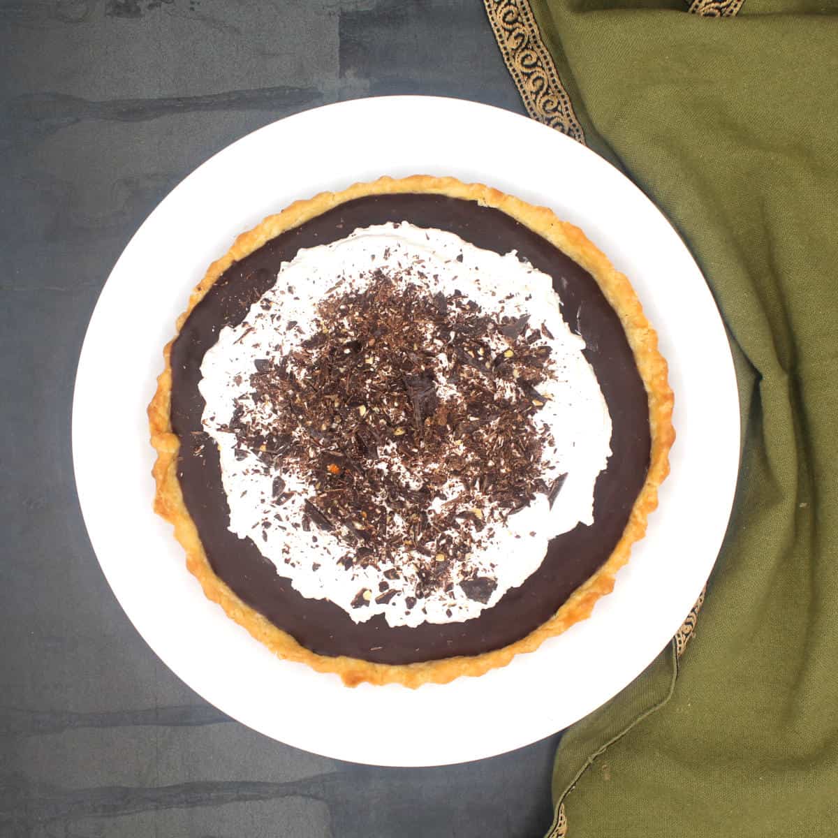 Vegan chocolate pie in plate with whipped cream and chocolate shavings.