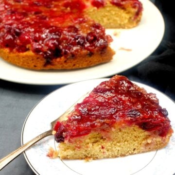 Vegan cranberry upside down cake slice in white plate with fork.