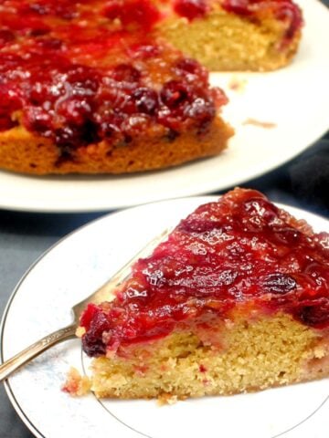Vegan cranberry upside down cake slice in white plate with fork.