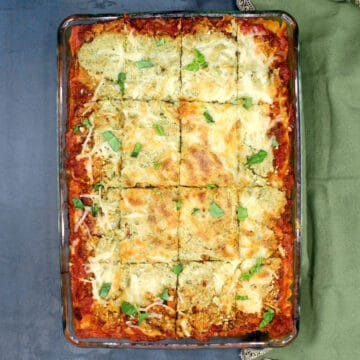 Vegan lasagna in glass baking pan with green napkin on side.