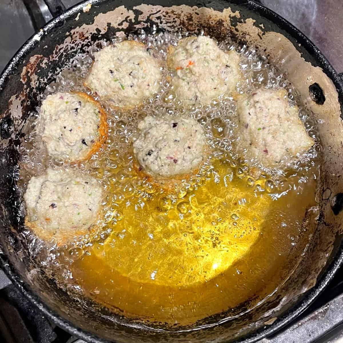 Black-eyed pea fritters in oil in frying pan.