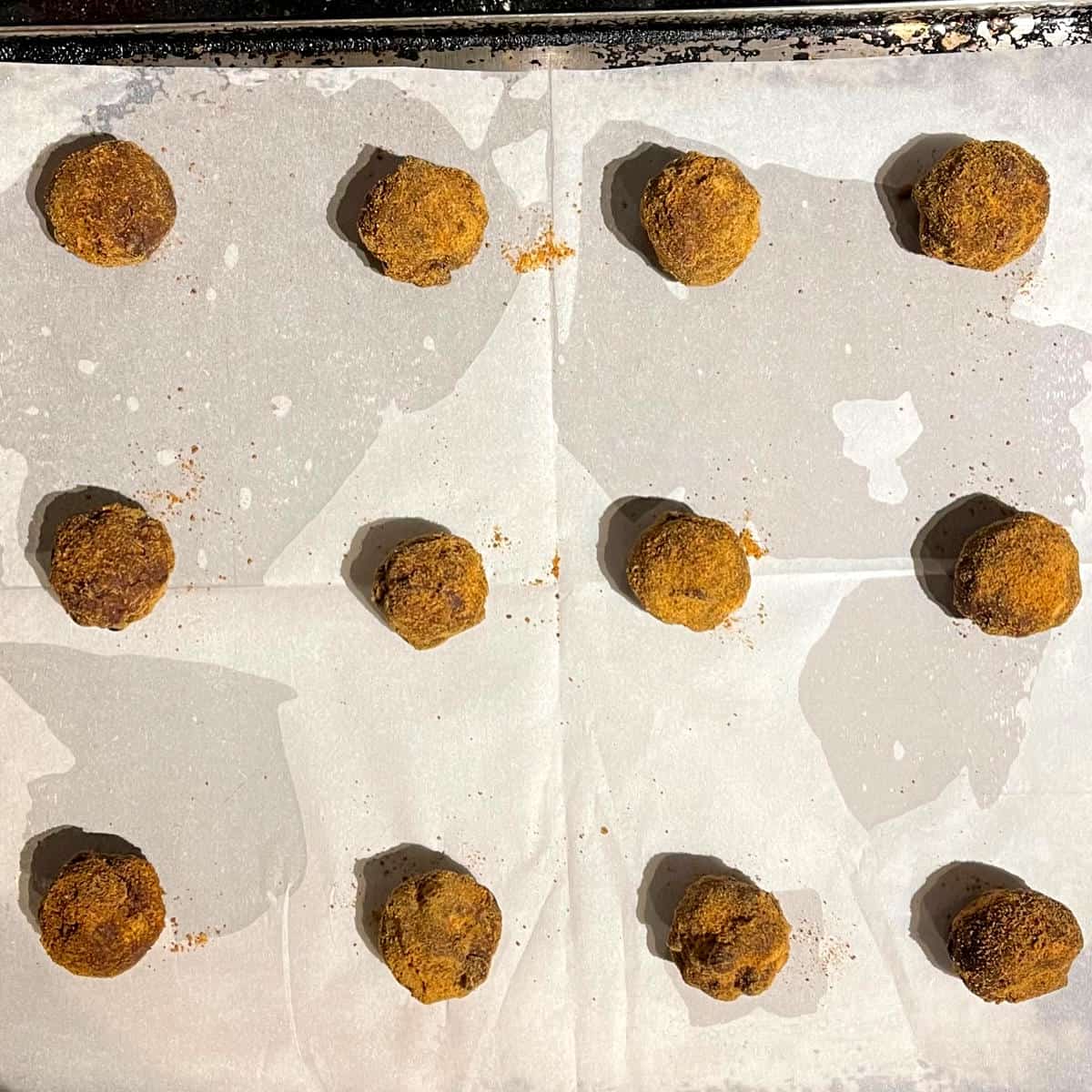 Cookie dough balls on parchment lined baking sheet.