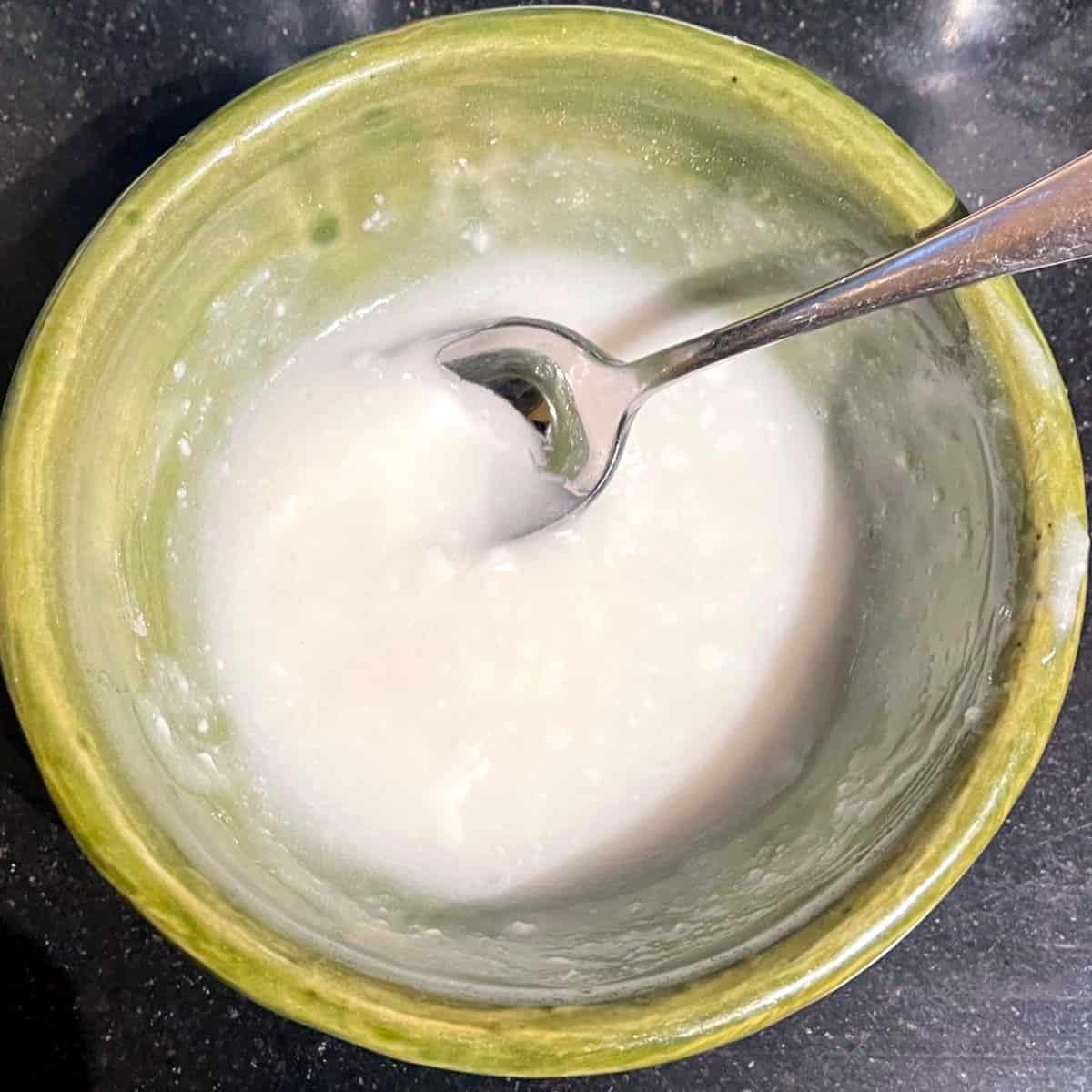 Cream cheese glaze mixed in bowl with spoon.