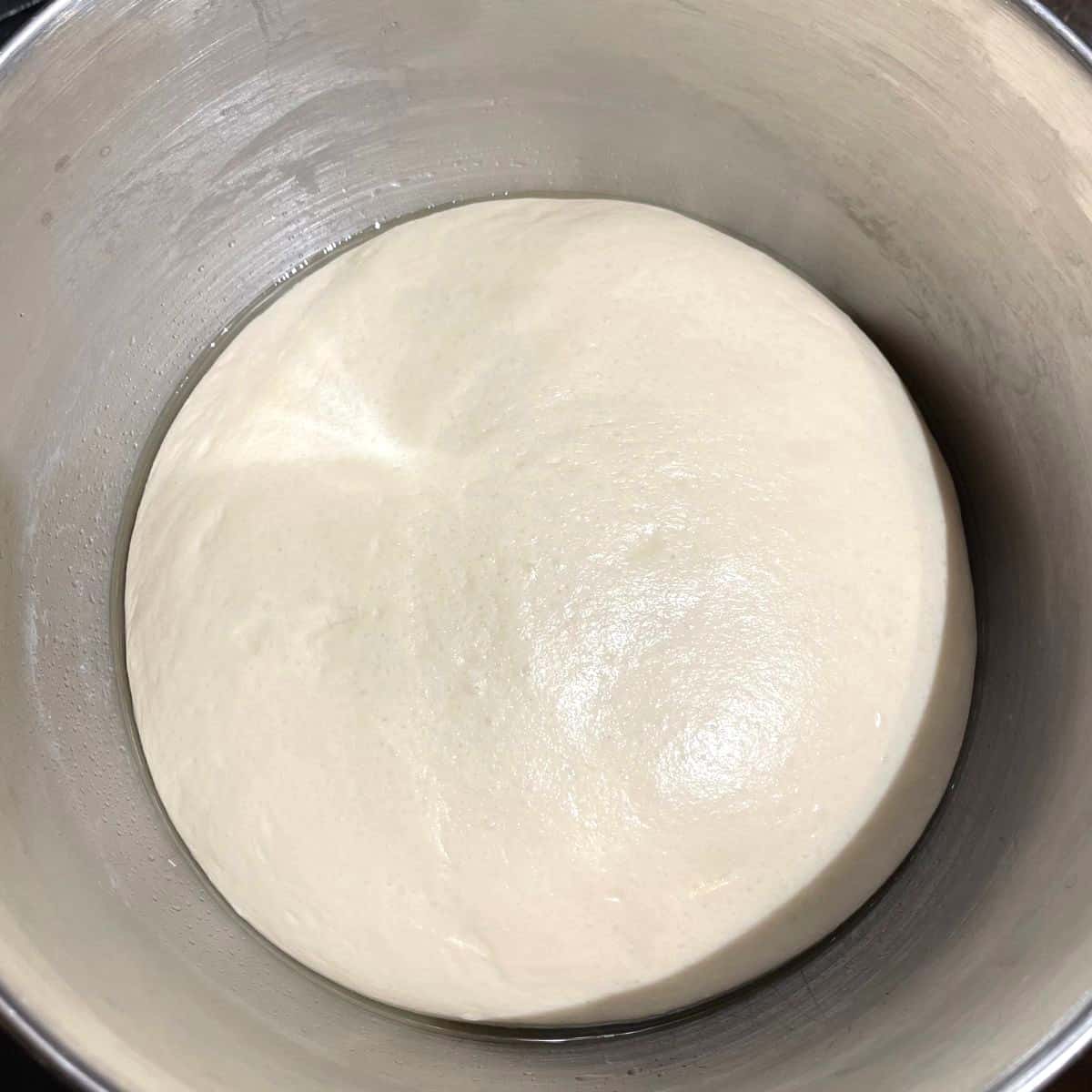 RIsen vegan challah dough in steel bowl.