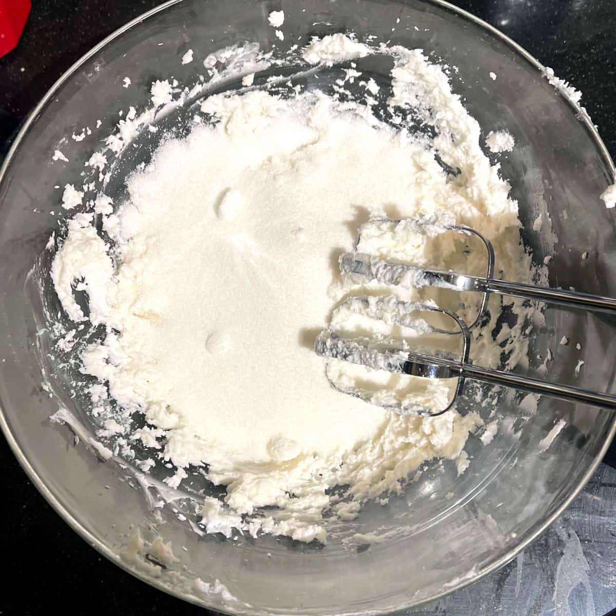 Sugar added to bowl with cream cheese and butter mixture.