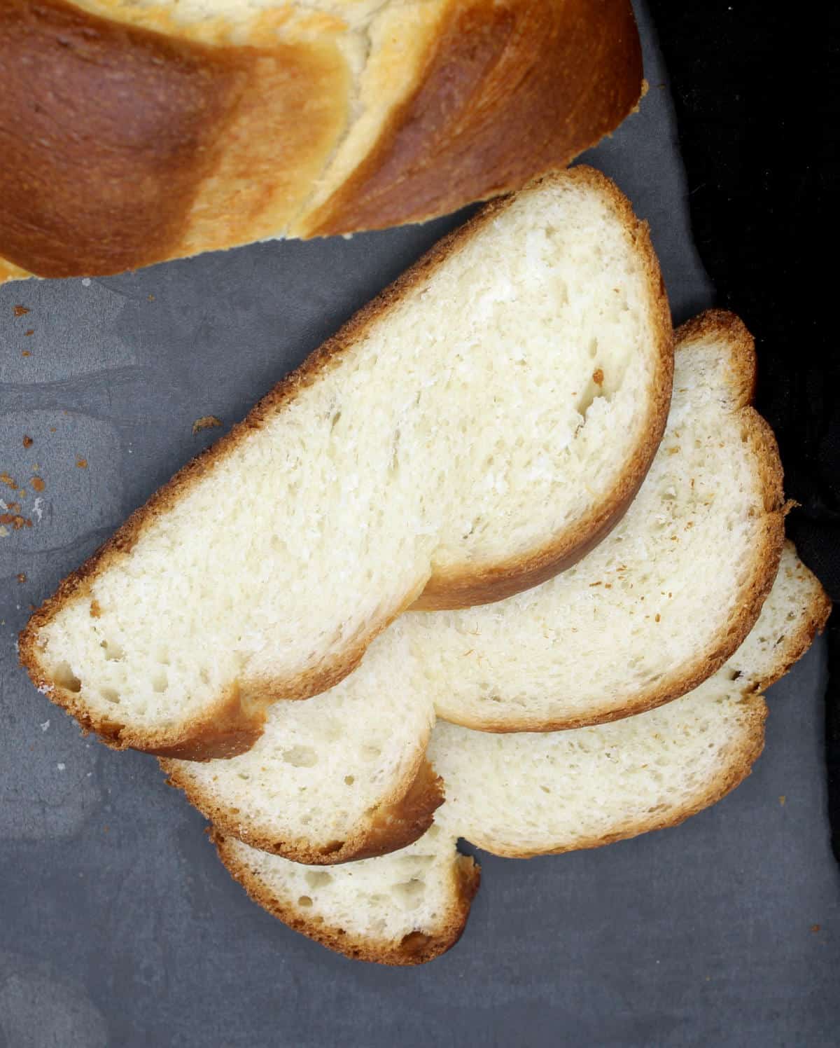 Slices of vegan challah bread on gray background.