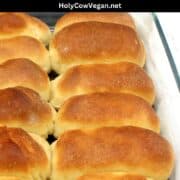 Vegan Parker House rolls with golden crust in baking dish with text that says "vegan parker house rolls".