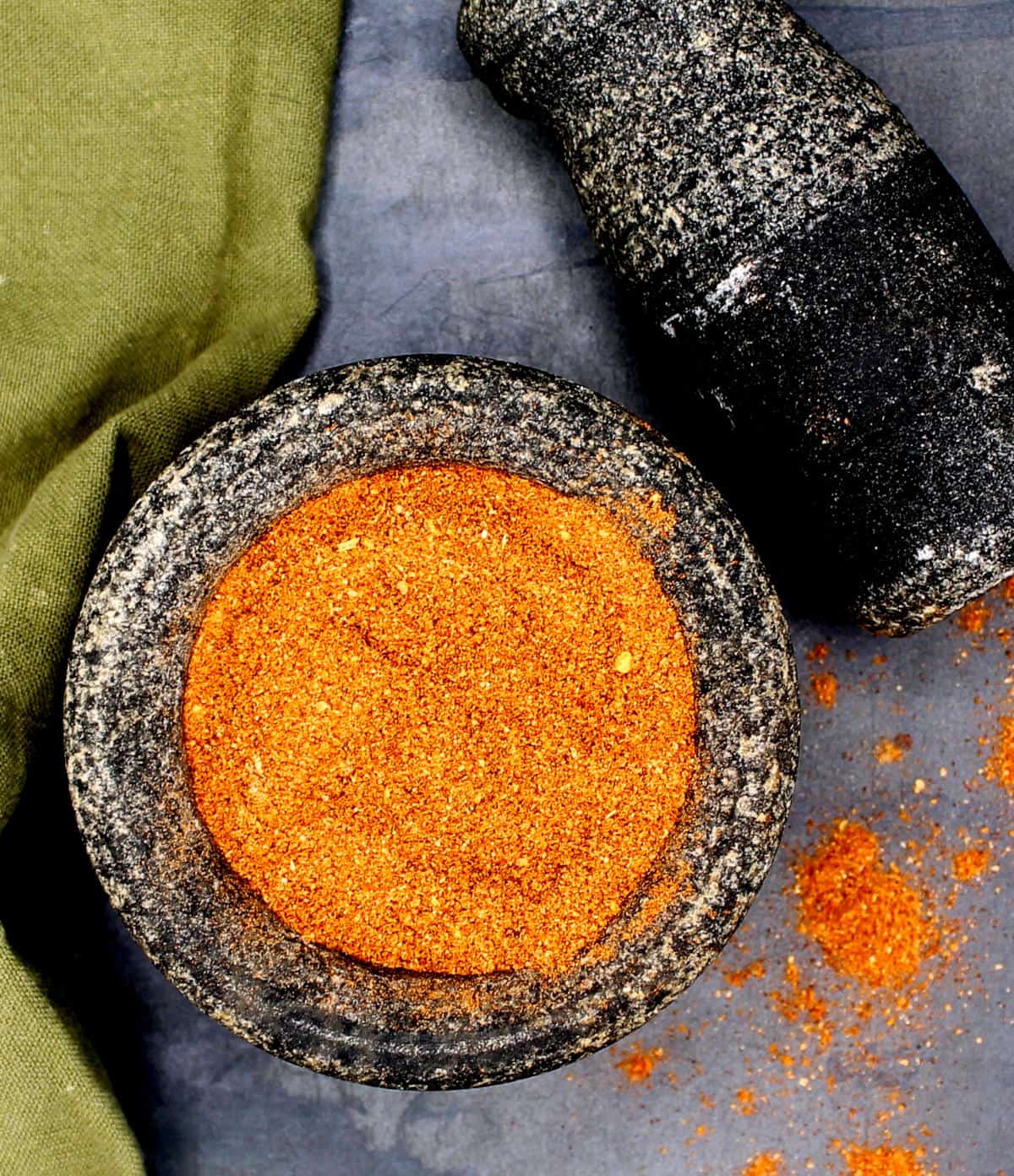 Ethiopian berbere spice mix in mortar and pestle with green napkin on side.