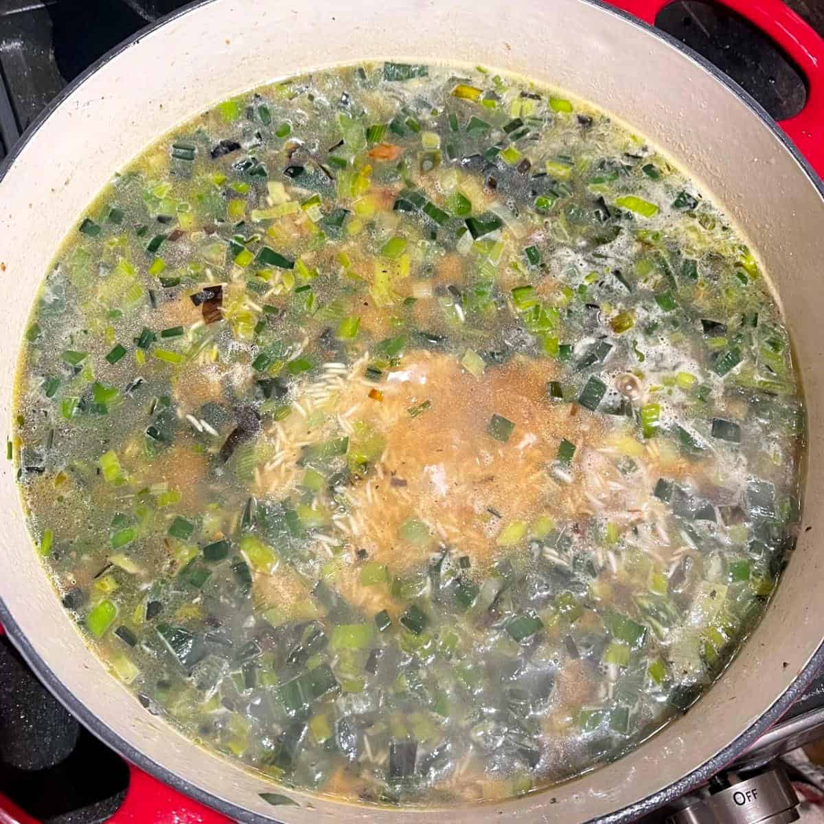 Water added to leeks and rice in skillet.