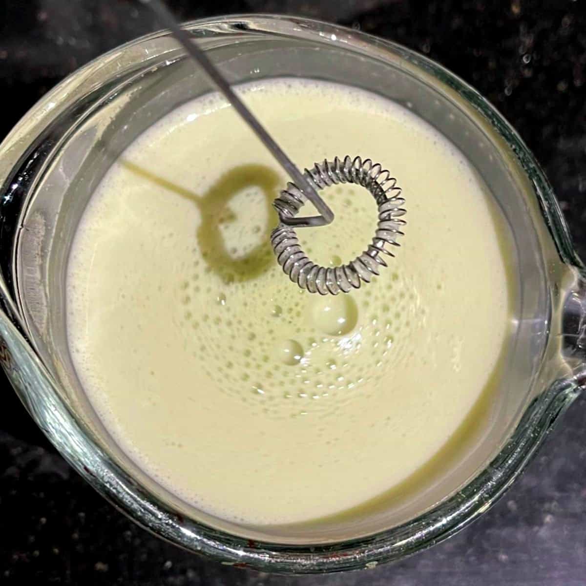 Matcha tea whisked with milk using a milk frother.