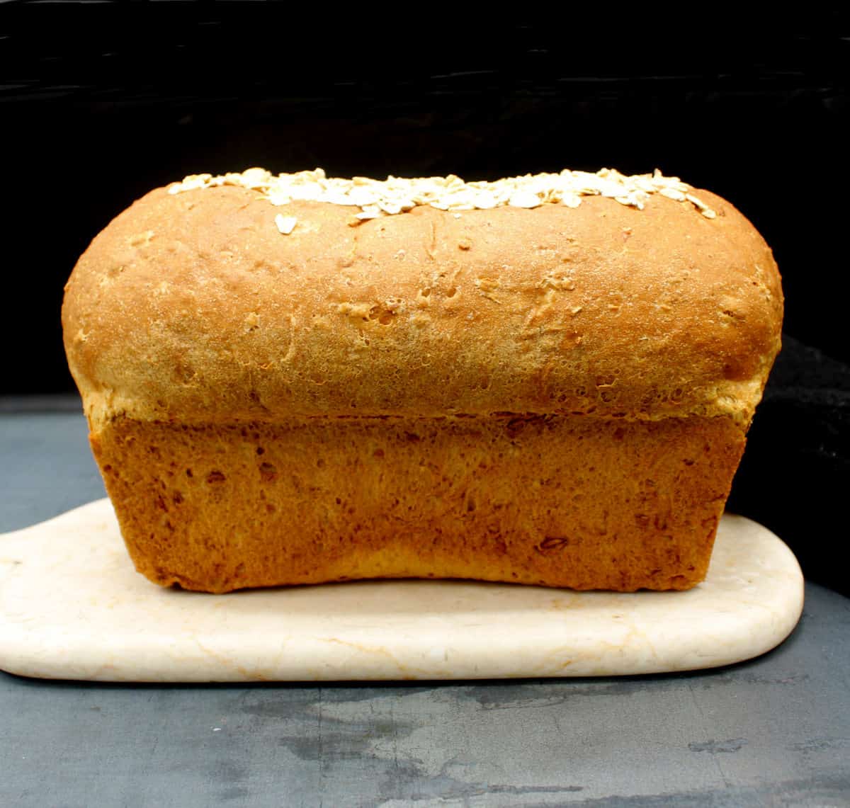 Loaf of oatmeal bread on marble board.