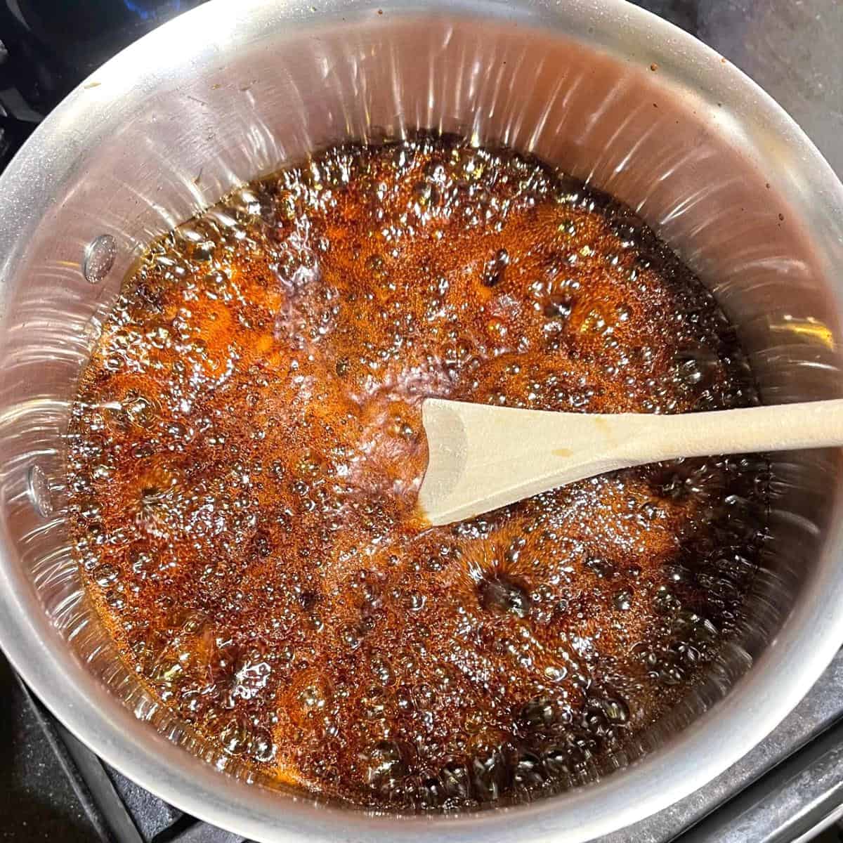 Jaggery boiling in saucepan with ladle.