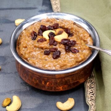 Sakkarai pongal in copper and steel bowl with spoon and with cashews and raisins for garnish.