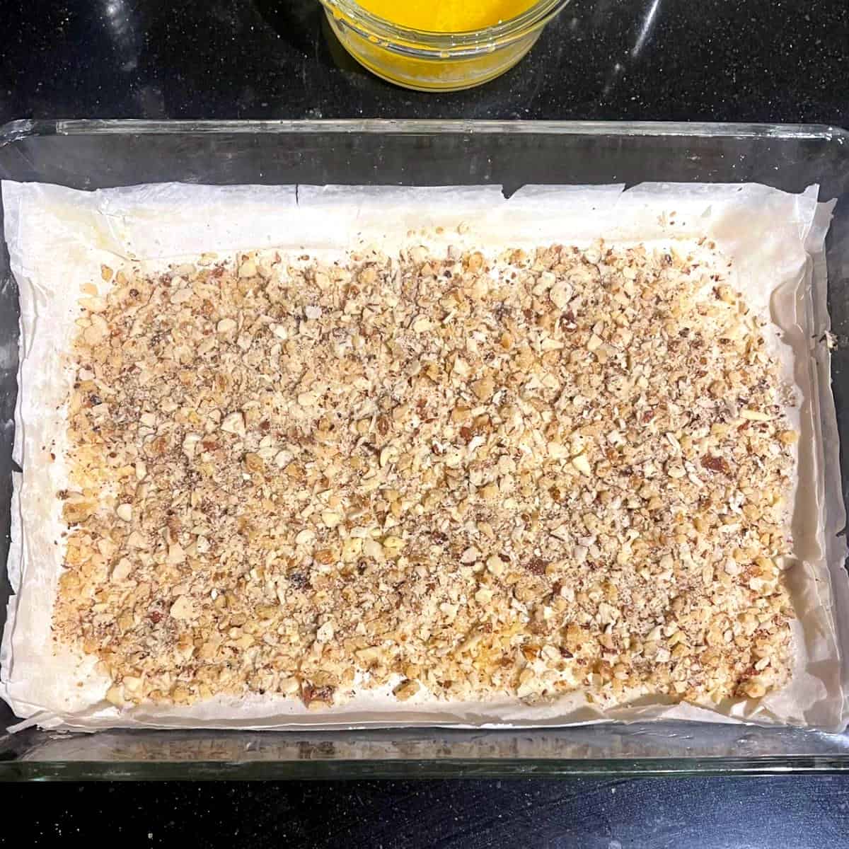Nuts layered over filo pastry in baking sheet.