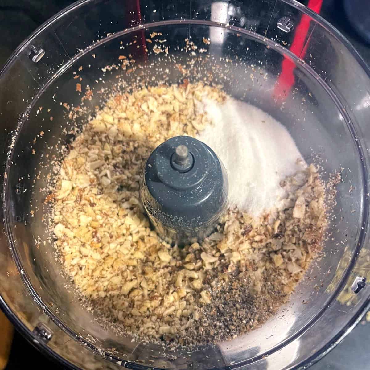 Nuts in food processor with sugar and cardamom.