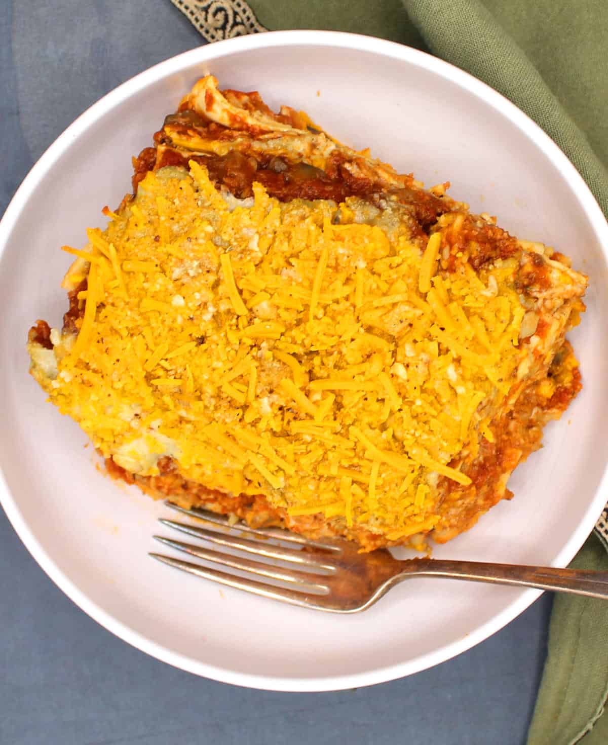 Slice of vegan lasagna in white bowl with fork.