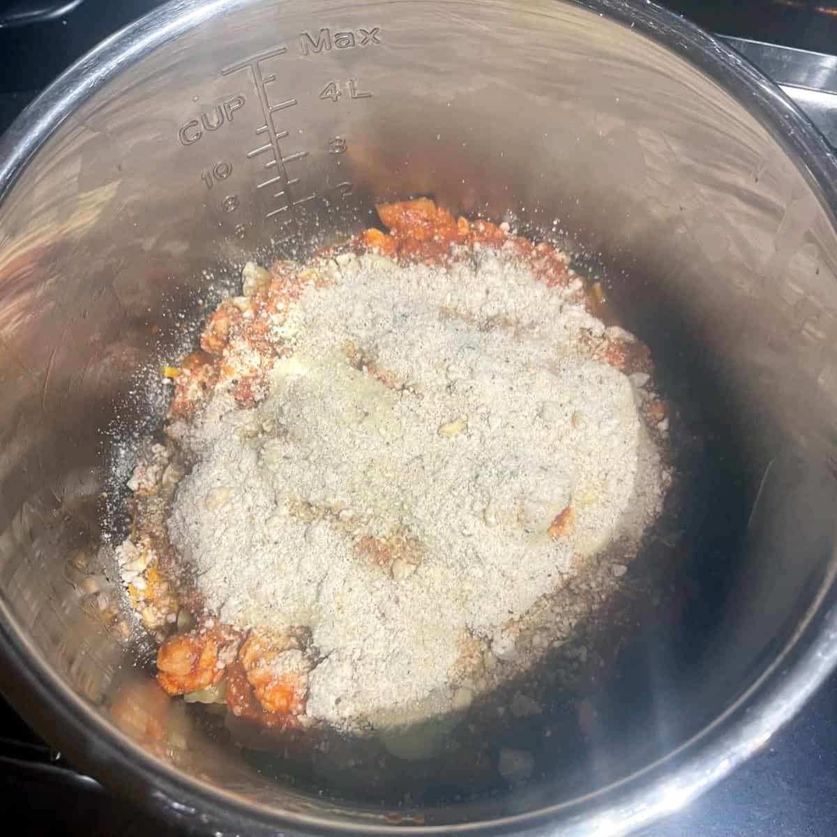 Parmesan cheese layer over tomato sauce in vegan crockpot lasagna.