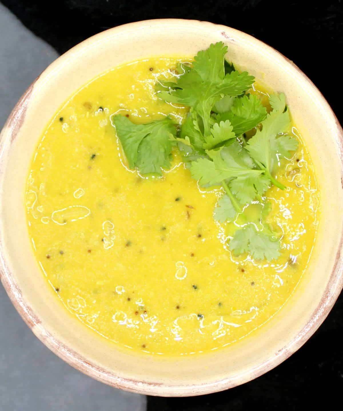 Bengali dal with panch phoron in bowl with cilantro garnish.